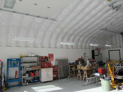 Metal quonset hut building with fiberglass insulation attached with plastic insulation pins